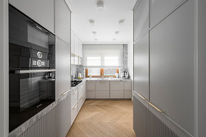 Modern grey kitchen with stone worktop and wallroom, fluted cuboards fronts and brass and golden details