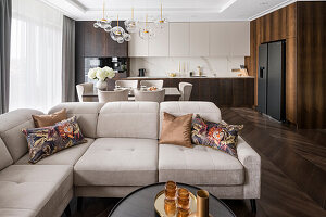 Upholstered sofa in cool beige in Hampton style open plan living room, dark brown color palette with gold accessories