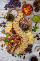 Appetizer board with bread, cheese, nuts, olive oil, tomatoes, and grapes