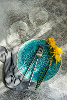 Minimalistische Tischdekoration mit türkisblauem Teller und Narzissen