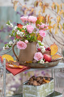 Autumn bouquet of snowberry (Symphoricarpos), roses and autumn leaves on shelf