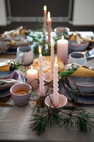 Festively laid dining table with candles, fir greenery and earthenware crockery