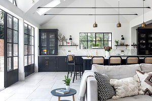 Open-plan kitchen with dining area and hanging pendant lights in black and white design