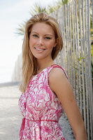Blonde woman in pink and white summer dress on the beach