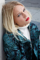 Young blonde woman in a white turtleneck sweater and transitional coat with leaf jacquard