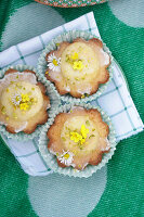 Blumige Muffins mit essbaren Blüten auf karierter Stoffserviette