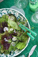 Gemischter Salat mit essbaren Blüten in gemusterter Schale