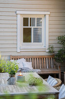 Tisch und Gartenbank unter dem Fenster auf der Terrasse