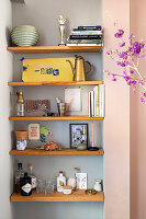 Wooden shelves in wall niche with books and decorative objects