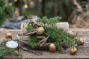 Adventsdeko, Eibenzweig mit vergoldeten Haselnüssen und historische Taschenuhr auf Tisch