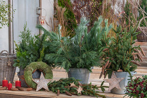 Adventsdeko auf Terrasse mit Kiefernzweigen und Fichtenzweigen, Adventskranz, Holzsterne, Kerzen auf Terrasse