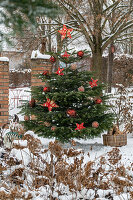 Geschmückter Christbaum im verschneiten Garten