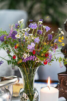 Flower arrangement with wildflowers and candle on the table