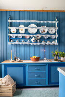 Blue kitchen with blue wood panelling and open shelf decorated with lace