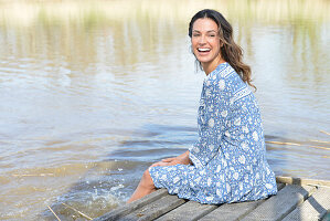 Brunette woman sitting on a wooden pier by the lake