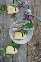 Serviette mit Primeln (Alpen auricel), Blatt als Namenskärtchen, Plätzchen in Schneckenform, Tischdeko