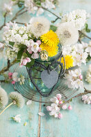 Bouquet of apple blossoms, lilac blossoms (Syringa) and dandelion (Taraxum) in a hanger jar, with hearts made of string and tin