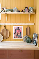 Yellow kitchen wall with shelves, chopping boards and decorative objects