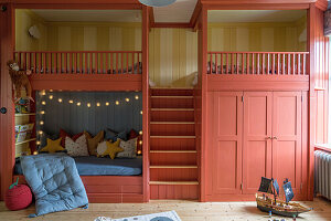 Children's room with bunk beds painted light red and fairy lights