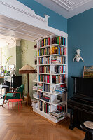 Bookcase in open-plan living area with blue and light green walls and piano