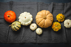 Various pumpkins on a grey table runner for Thanksgiving