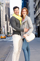 Laughing couple stands on the street with skyscrapers
