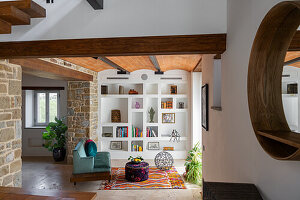 Open-plan living area with shelving wall, vaulted ceiling and living room furniture