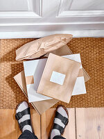 Stack of delivered cardboard parcels on a door mat next to apartment entrance