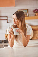 Smiling woman holding mug in kitchen\n