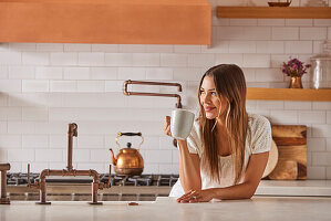 Lächelnde Frau mit Becher in der Hand in der Küche