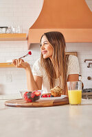 Lächelnde Frau genießt gesundes Frühstück in der Küche