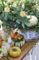 Herbstliche Deko mit Kürbissen, Chrysanthemen, Rosen, Mühlenbeckia