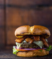 Beef-Burger mit Speck, Schweizer Käse, Salat, Tomate und roten Zwiebeln