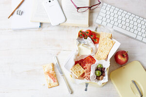 Packed lunch with cheese, crackers, tomatoes, olives, salami and apples
