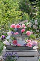 Selbstgebautes Etagere aus alter Gießkanne mit rosa Rosenblüten