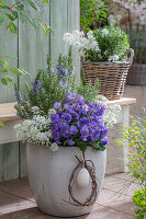 Ribbon flower (Iberis sempervirens) 'Candy', rosemary and primrose (Primula) 'Chrystal Fountai' in a plant pot on the patio with an Easter egg in a wreath