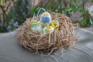 Easter nest made of straw with self-painted Easter eggs with flower decoration