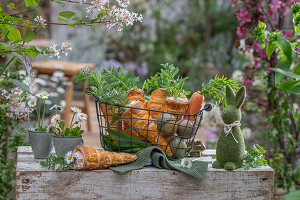 Blätterteigtüten im Ofen gebacken, gefüllt mit Karotten-Dill-Sauresahnesoße im Drahtkorb und gefärbten Eiern, Kräuter als Deko, Gänseblümchen in Tasse als Vase, Osterhasenfigur