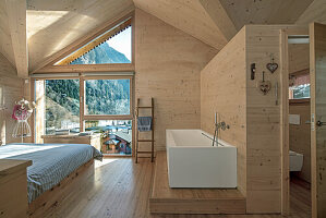 Schlafzimmer im Chaletstil mit freistehender, eckiger Badewanne und Panoramablick auf die Berge