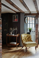 Antique armchair and tea trolley in rustic living room with exposed wooden beams