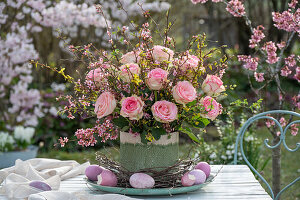 Bouquet of forsythia branches and roses, colorful Easter eggs and twigs as table decoration