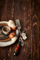 Autumnal, rustic table setting with fresh porcini mushrooms and coarsely crushed pepper