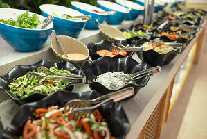 Salads and fresh vegetables in bowls on buffet table in hotel