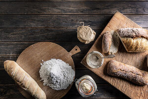 Mehl, Brot und Gläser mit Roggensauerteig