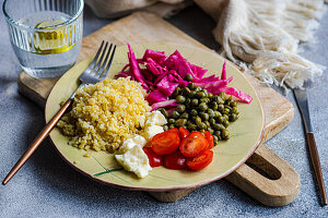 Bulgur dazu fermentierter Kohl, Kapern, Käse und Kirschtomaten