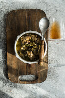 Traditional Georgian dish Chakapuli in a bowl and a glass of amber wine