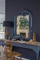 Console table with antique mirror and eucalyptus branches in front of dark grey painted wall