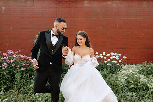 Bride and groom walking on sidewalk in town