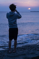 Young person on the beach looking at horizon at sunset in Normandie