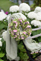 Autumn wreath with hydrangea, sedum and roses on garden chair